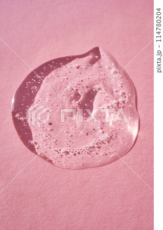 Drop of serum shimmering in the sun on a pink background. 114780204