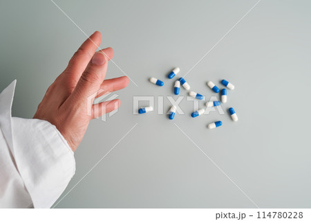 Hand reaches out to a white and blue pill on a blue background. 114780228