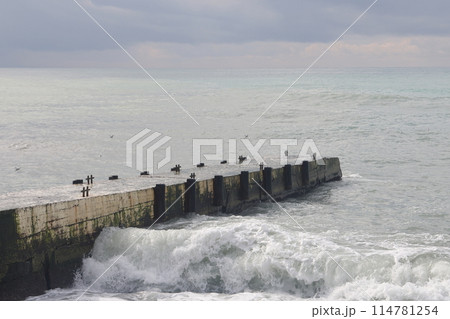 Sochi, Russia 05.07.2021. Breakwater pier summer black sea cloudy. Sochi, Russia 05.07.2021. Breakwater pier summer black sea cloudy. 114781254