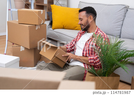 A young man unpacks boxes on his moving day, finding a moment of calm on the sofa in his new home, symbolizing the essence of relocation 114781987