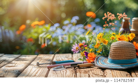 A wooden table covered with a gardening hat and various tools, set against a blurred natural background. Generative AI A wooden table covered with a gardening hat and various tools, set against a blurred natural background. Generative AI 114782597