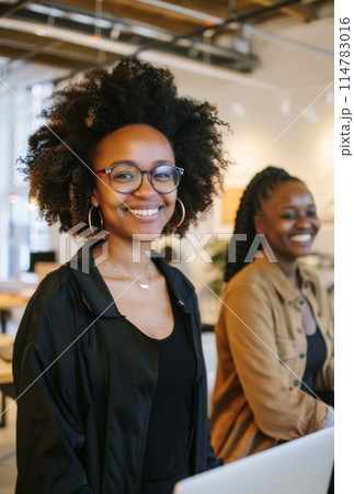 Smiling women standing together in a modern office setting 114783016