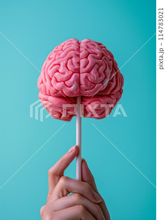 Creative concept of a hand holding a brain-shaped lollipop against a blue background 114783021