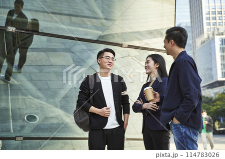 young asian adults standing talking on street young asian adults standing talking on street 114783026