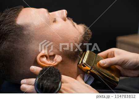 Client during beard trimming in the barbershop. Client during beard trimming in the barbershop. 114783812