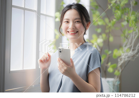 窓際でスマホを持って考える女性 カメラ目線 窓際でスマホを持って考える女性 カメラ目線 114786212