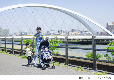 川の土手をベビーカーを押しながら歩く親子 川の土手をベビーカーを押しながら歩く親子 114786709