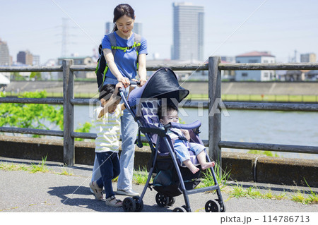 川の土手をベビーカーを押しながら歩く親子 川の土手をベビーカーを押しながら歩く親子 114786713