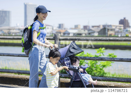 川の土手をベビーカーを押しながら歩く親子 114786721