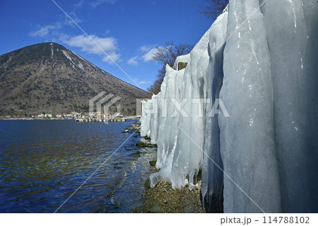 中禅寺湖東岸歌ヶ浜のしぶき氷の壁に男体山 114788102