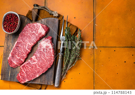 Raw Denver beef meat Steak with pink pepper and thyme. Orange background. Top view. Copy space 114788143