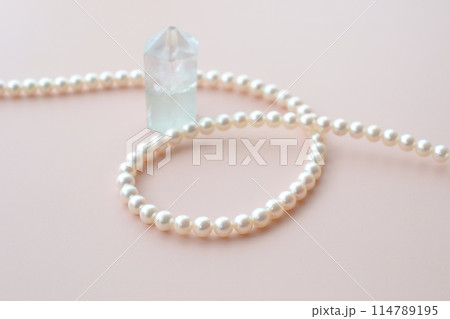 薄ピンクの背景にパールホワイトパールのネックレスと白い丸いフレーム 114789195