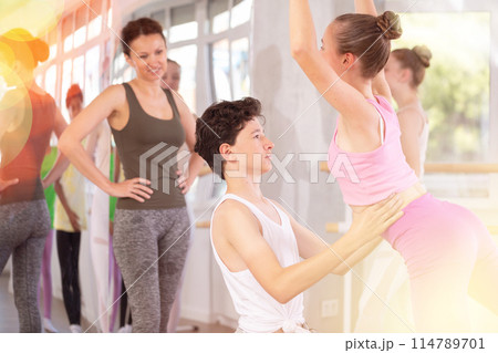 Teenage girl practicing ballet positions in pair with boy in dance studio Teenage girl practicing ballet positions in pair with boy in dance studio 114789701
