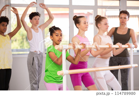 Teenage girls practicing plie position of ballet during choreography classes 114789980