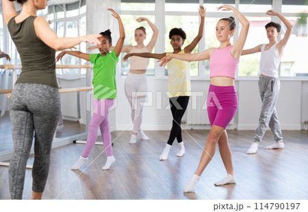 Teen girl practicing ballet movements at group class 114790197