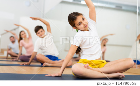 Girl practicing yoga at studio with family 114790358