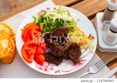 Turkish kofte, grilled veal meatballs with vegetables and bread 114790465