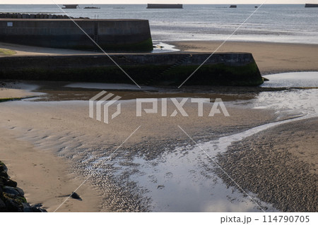 Closeup view of seawall blue sky and clouds. Sand, sea, ocean and sun. Normandy village of Gold Beach France. Tourism. High quality photo 114790705