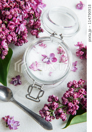 Natural Lilac Sugar in a Glass Jar Surrounded by Fresh Lilac Blooms 114790918