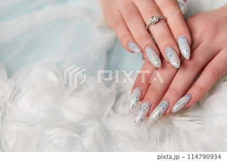 Elegant Hands Featuring Sparkling Ring and Blue Floral Manicure on Delicate White Fabric Elegant Hands Featuring Sparkling Ring and Blue Floral Manicure on Delicate White Fabric 114790934