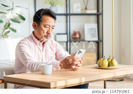 自宅でスマホを操作するミドル男性。 自宅でスマホを操作するミドル男性。 114791061