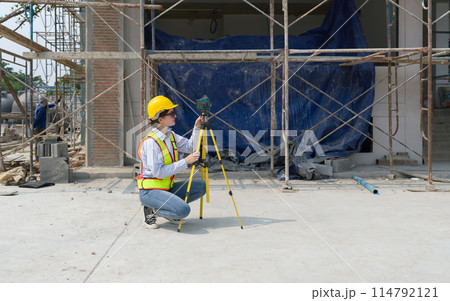 A construction worker is using a laser gauge to capture the setting of masonry, plastering and wall work at a building site. 114792121