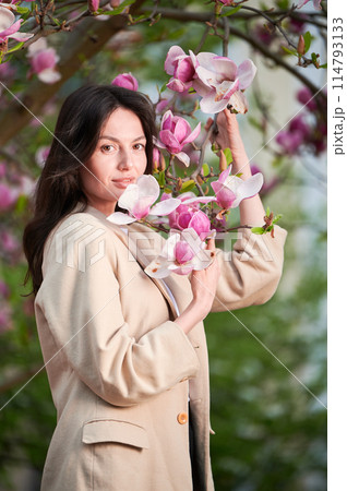 Woman allergic enjoying after treatment from seasonal allergy at spring. Portrait of happy young woman smiling in front of blooming magnolia tree at springtime. Spring allergy concept. Woman allergic enjoying after treatment from seasonal allergy at spring. Portrait of happy young woman smiling in front of blooming magnolia tree at springtime. Spring allergy concept. 114793133
