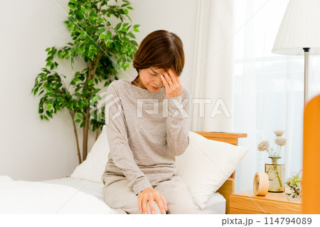 病院の個室で寝起きで頭を抱える50代から60代のシニアの女性 病院の個室で寝起きで頭を抱える50代から60代のシニアの女性 114794089