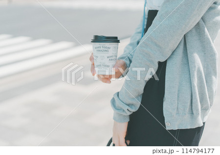 ホットコーヒーをテイクアウトした働く女性の手元 114794177