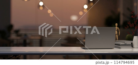 A computer on a tabletop with a blurred background of a beautiful sunset view through the balcony. A computer on a tabletop with a blurred background of a beautiful sunset view through the balcony. 114794695