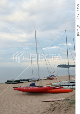 Catamarans with masts on lake shore. Catamarans with masts on lake shore. 114795399