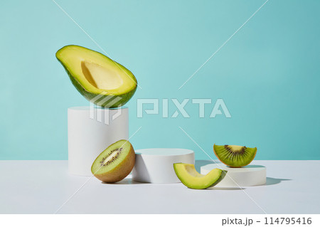Plenty empty podiums displayed on white table top with some pieces of avocado and kiwi random arranged on, over light blue background. Blank space for presentation, from front view Plenty empty podiums displayed on white table top with some pieces of avocado and kiwi random arranged on, over light blue background. Blank space for presentation, from front view 114795416