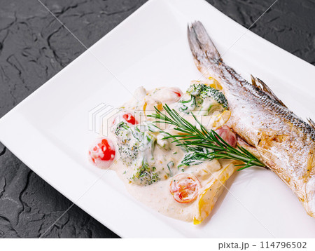 fish with broccoli and sauce on a white plate 114796502