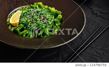 Fresh green seaweed salad with sesame seeds on dark plate 114796759