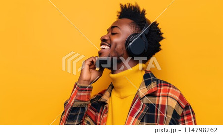 Man with on yellow background listening to music with headphones Man with on yellow background listening to music with headphones 114798262