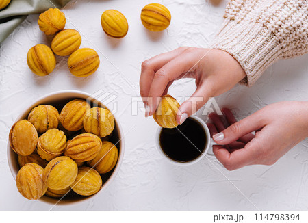 Hand picking a cookie with coffee on table Hand picking a cookie with coffee on table 114798394