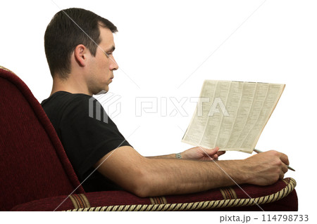 Young man in chair reading a newspaper with an advertisement 114798733