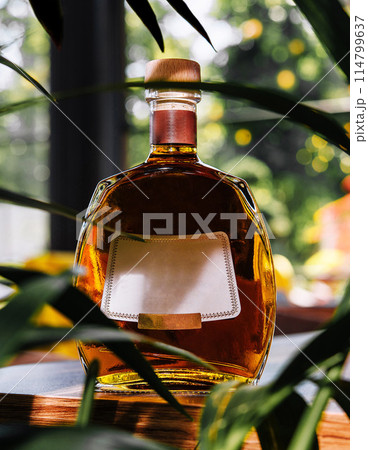 Elegant whiskey bottle with blank label amidst greenery 114799637
