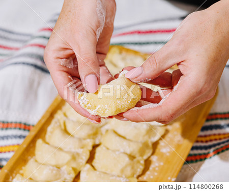 Close-up of hands shaping pierogi on a kitchen board Close-up of hands shaping pierogi on a kitchen board 114800268