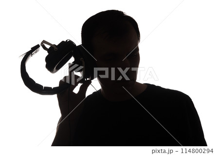 Silhouette of a young man with a smartphone with headphones 114800294
