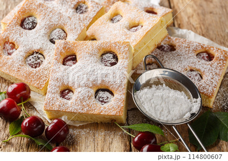 Fruity cherry cake known as Bublanina sprinkled with powdered sugar closeup on the parchment. Horizontal 114800607