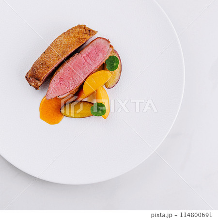 Gourmet duck breast with peach slices on white plate 114800691