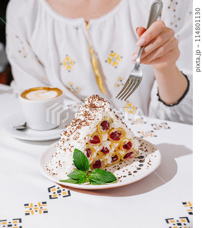 Woman enjoying delicious cake from rolled pancakes with cream, cherries Woman enjoying delicious cake from rolled pancakes with cream, cherries 114801130