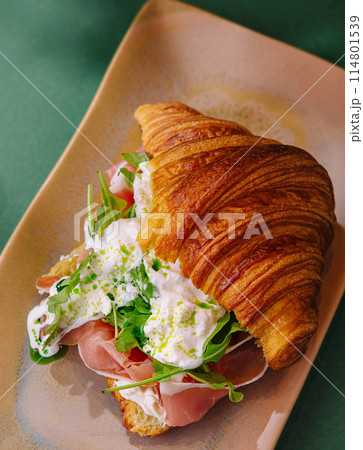 Gourmet croissant sandwich with prosciutto and arugula 114801539