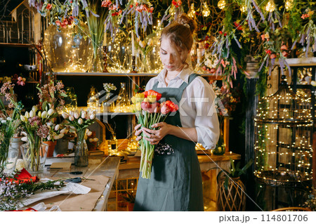 A woman in her florist shop collects bouquets of flowers. The concept of a small business. Bouquets of tulips for the holiday on March 8. 114801706