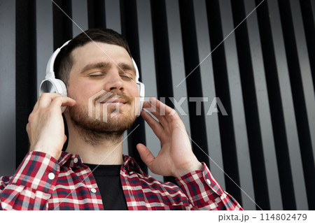 Attractive young guy listens to music in headphones 114802479