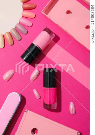 Nail polishes with accessories on a pink background 114802504