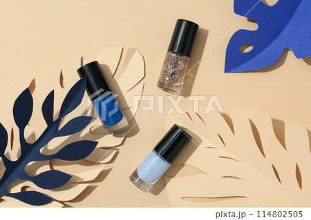 Multicolored nail polishes with decorative paper leaves 114802505