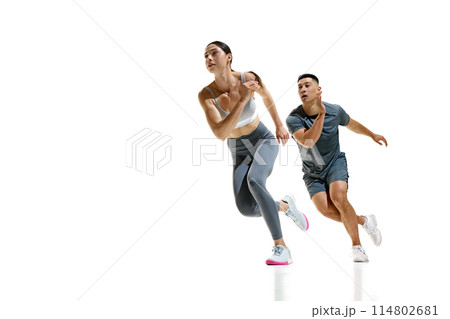 Man and woman wearing sports clothes mid-stride during sprinting exercise against white studio background. Teamwork. Man and woman wearing sports clothes mid-stride during sprinting exercise against white studio background. Teamwork. 114802681