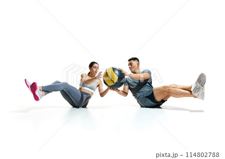 Athletic man and woman working out together with medicine ball against white studio background. Workout. Athletic man and woman working out together with medicine ball against white studio background. Workout. 114802788